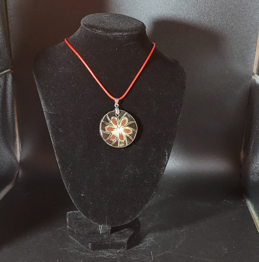 Jolie fleur en grès émaillé aux couleurs vieux rose et beige clair sur fond noir.
