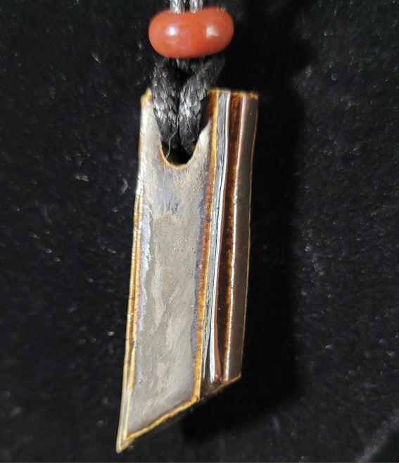 Collier pour femme ou homme, forme géométrique de couleur brun nacré réhaussé d'une perle minérale. Gros plan