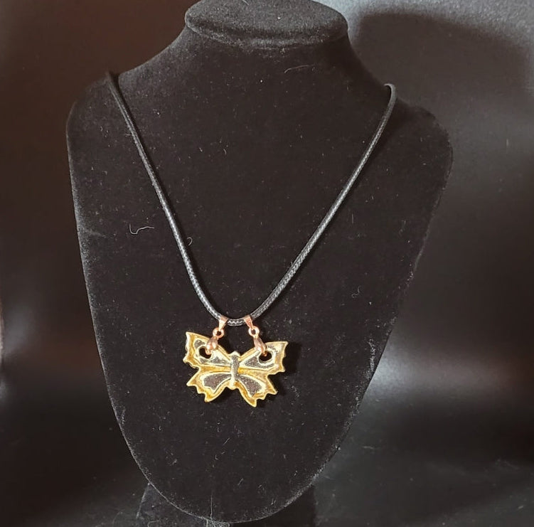 Pendentif artisanal, pièce unique fait main aux couleurs ocre et noir avec deux bélières. Vue portée