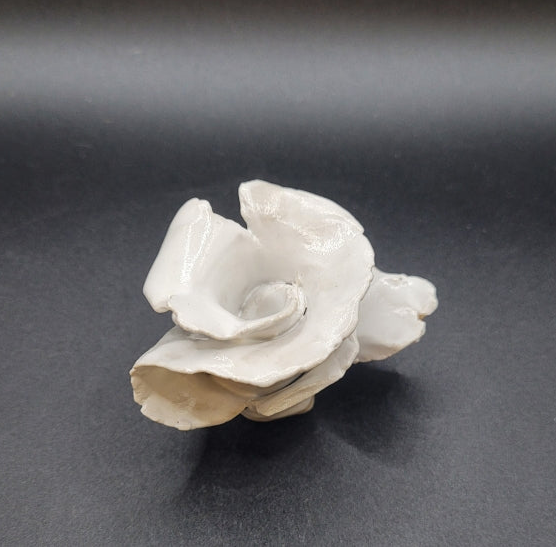 Rose en grès émaillé blanc. De petite taille, elle ravira la décoration d'un table ou tout espace ayant besoin d'un clin d'œil artistique. Vue de trois quart