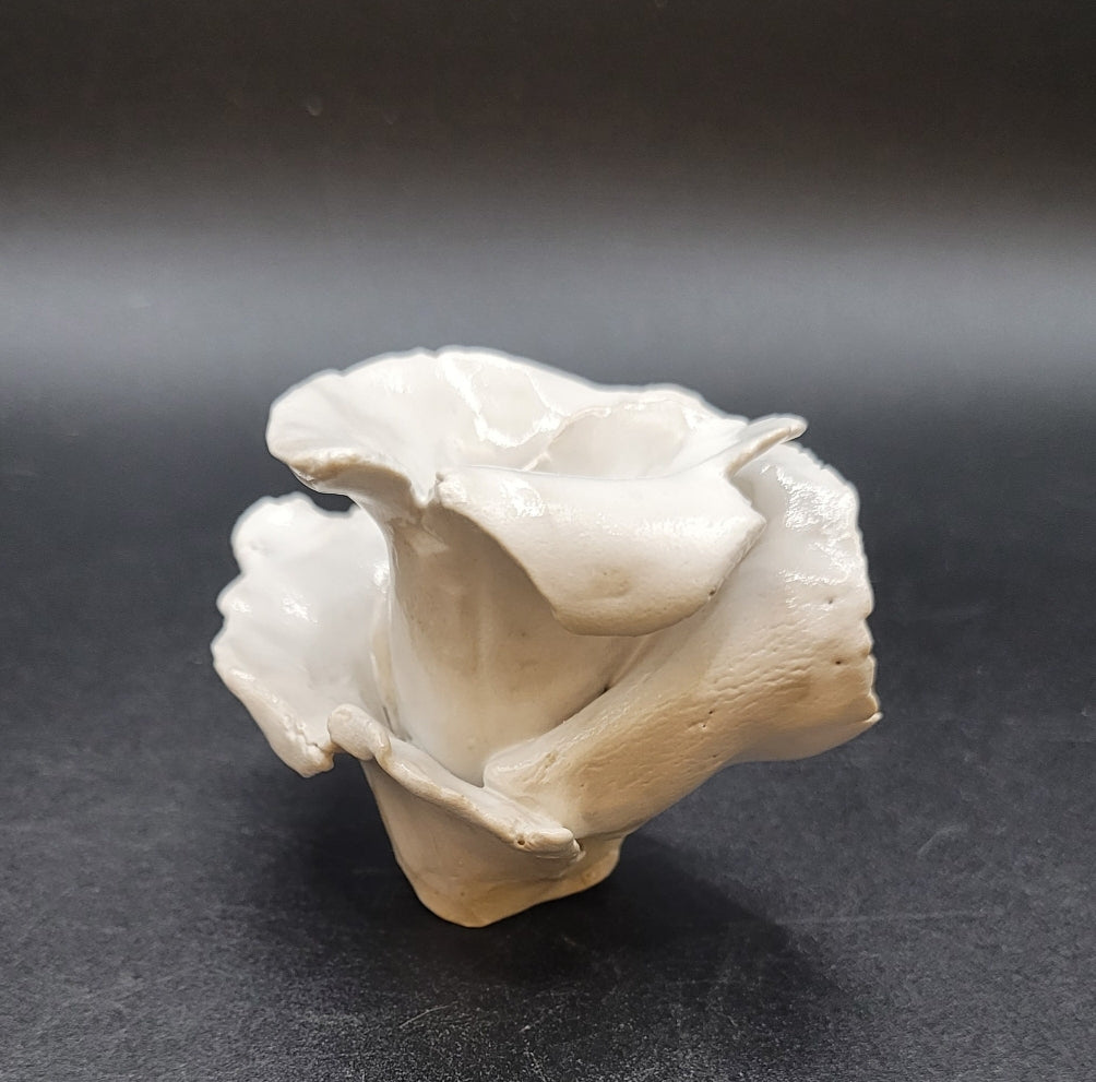 Rose en grès émaillé blanc. De petite taille, elle ravira la décoration d'un table ou tout espace ayant besoin d'un clin d'œil artistique. Vue de côté